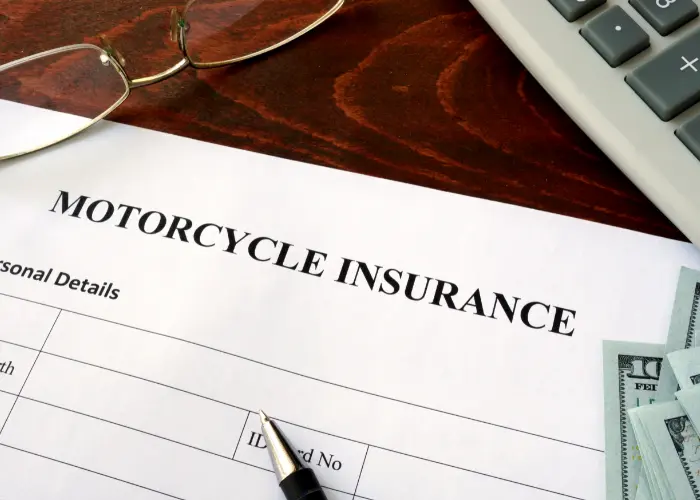 Motorcycle insurance form and dollars on the table.